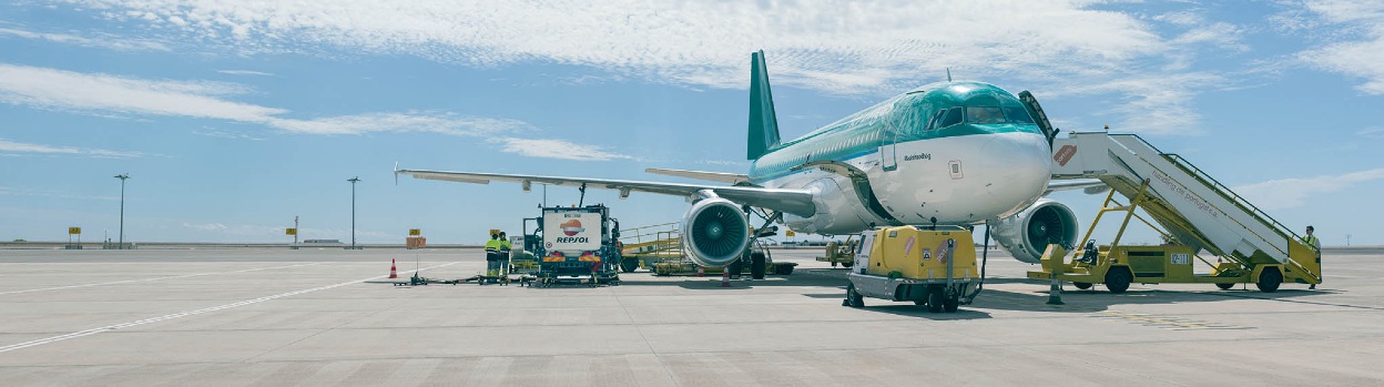 Carga de combustible de un avión en el aeropuerto desde un camión de repostaje con marca Repsol.