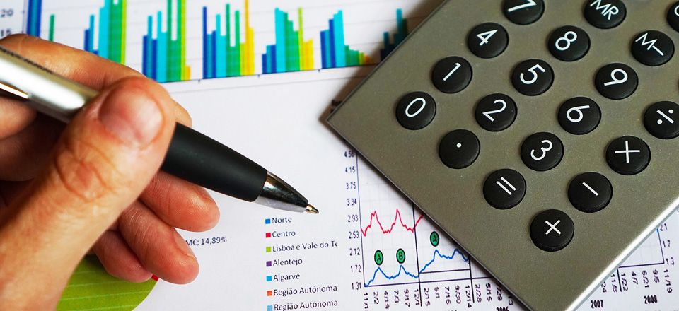 Repsol International Finance. Vista de un calculadora una mano sujetando un bolígrafo y varios documentos con gráficas 