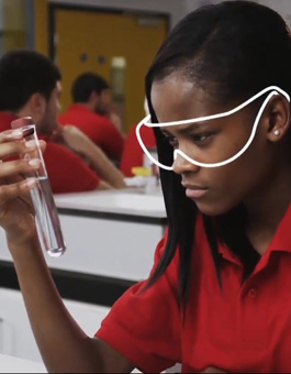 Una chica con gafas de seguridad examina el contenido de un tubo de ensayo 