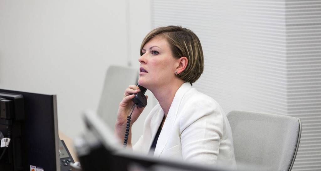 Mujer de blanco habla por teléfono en una oficina