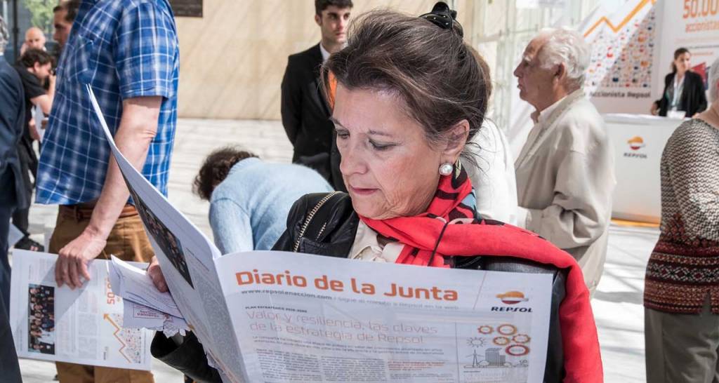 Mujer en un hall leyendo un periódico con el título: Diario de la Junta