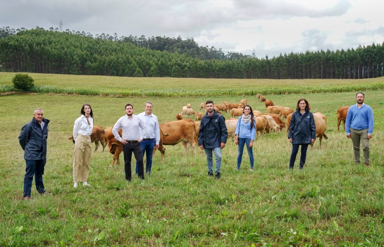 Varias personas del proyecto posando en un campo con vacas de fondo